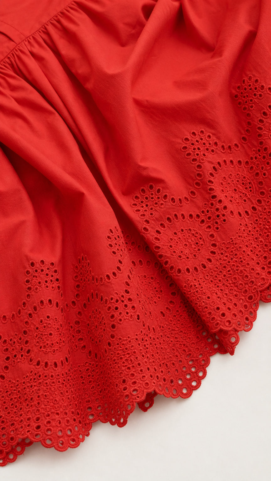 Close-up detail of red fabric and eyelet embroidery hem