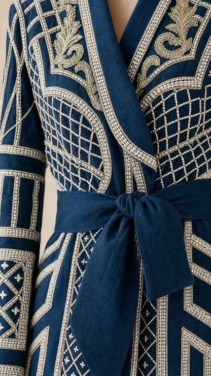 Close-up detail of lapel, embroidery, and tie belt on navy coat
