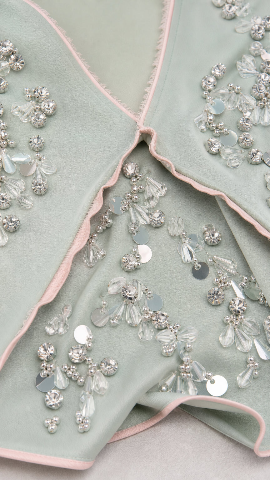 Close-up of beadwork and contrast piping details on sage green dress