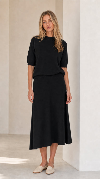 Woman wearing black knit top and matching midi skirt set