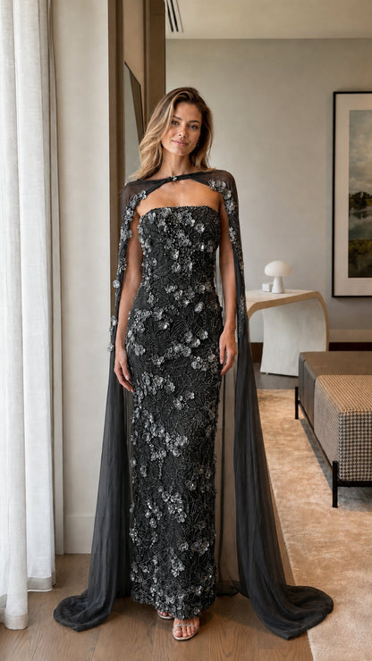 Black strapless column evening gown adorned with 3D florals and matching black cape