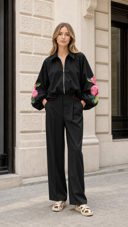 Model wearing black two-piece set with pink floral embroidery on balloon sleeves