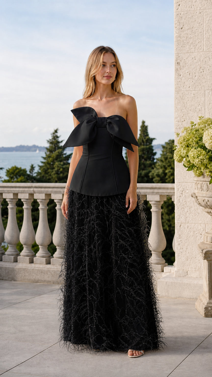Front view of model wearing black color variant of the bow corset and feather skirt set