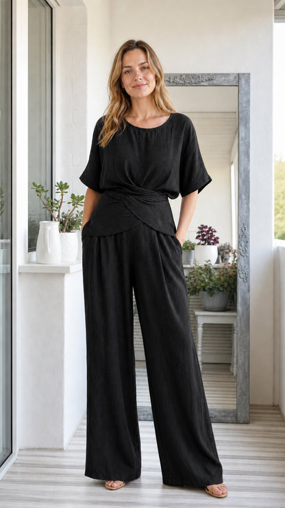 Model wearing black two-piece short sleeve twist top and wide leg pants set