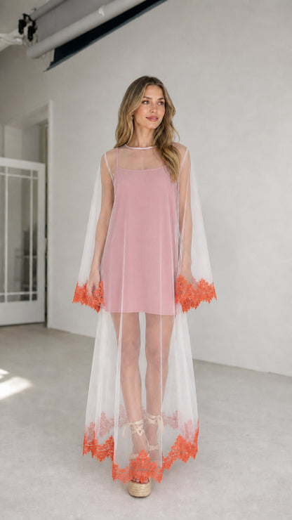 Model wearing pink inner dress with white embroidered mesh duster