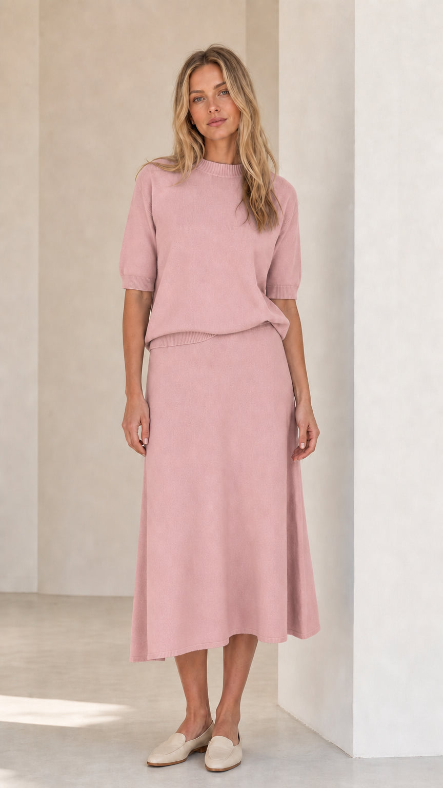 Woman wearing pink knit top and matching midi skirt set