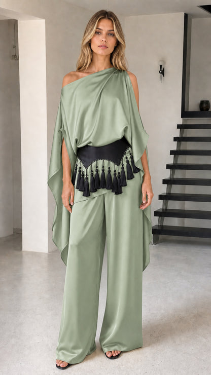 Model wearing sage green draped one-shoulder pant set with black waist belt