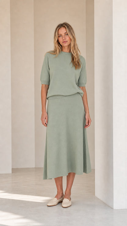 Woman wearing sage green knit top and matching midi skirt set