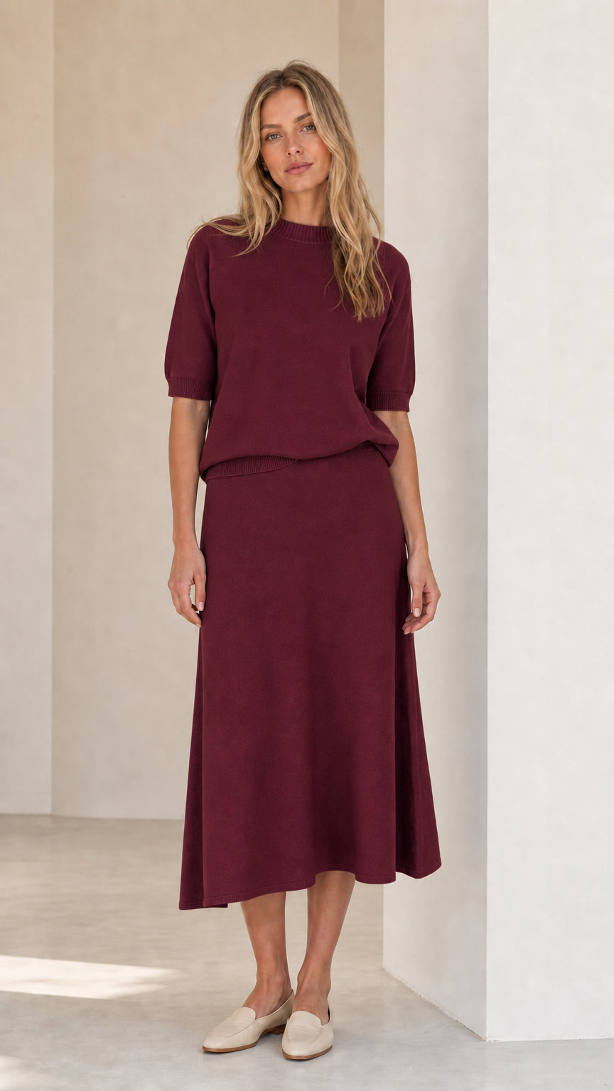Woman wearing burgundy knit top and matching midi skirt set