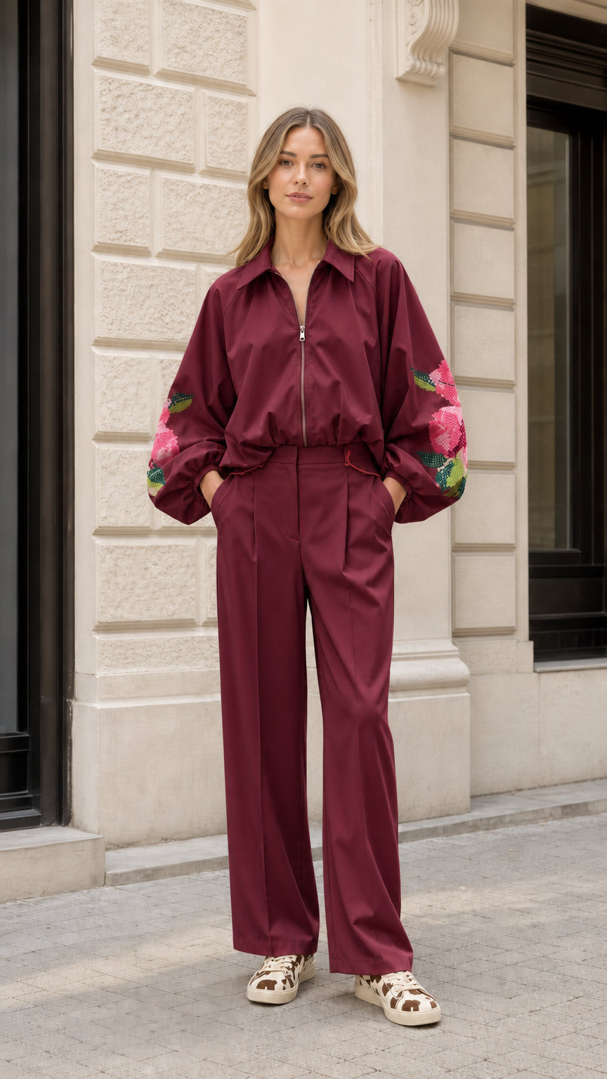 Model wearing burgundy wine two-piece embroidered jacket and wide-leg trouser set