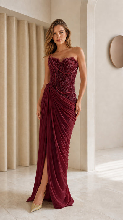 Model wearing burgundy strapless draped corset evening gown